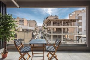 uma mesa e cadeiras numa varanda com vista para a cidade em Stylish Urban Suites em Atenas
