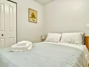 a bedroom with a large bed with white sheets at Burnaby Metrotown Cozy 3 Bedroom Suite in Burnaby