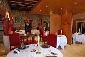 un restaurante con mesas blancas, sillas rojas y registrador en Hotel La Chaumiere, en Dole