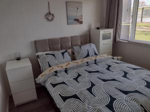 a bedroom with a bed with a black and white comforter at 19 Seadell in Hemsby