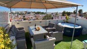 eine Terrasse mit einem Tisch und Stühlen sowie einem Whirlpool in der Unterkunft Apartment Beta - 2 Bedrooms, Private Rooftop Patio with Hot Tub, BBQ and View in Ferragudo