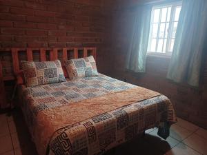um quarto com uma cama com uma parede de tijolos em CABAÑA LA GRULLA em Santa Verónica