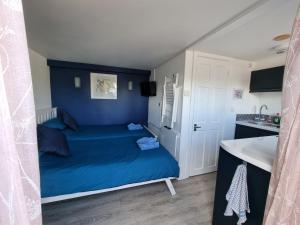 een slaapkamer met een blauw bed en een wastafel bij Lovely private studio room with own kitchen and bathroom. Set in the popular area of Shiphay in Torquay and only a short walk from Torbay Hospital in Torquay