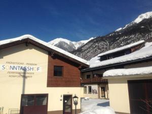a ski lodge with snow covered mountains in the background at Sonntagshof Ferienwohnungen Apartments in Förolach