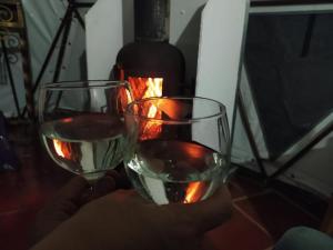 una persona con dos copas de vino delante de una botella en Glamping Bosque del Colibri, en Guatavita