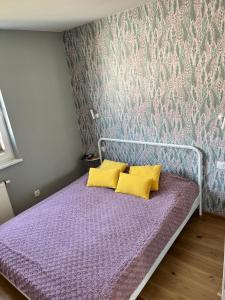 1 dormitorio con cama morada y almohadas amarillas en KAPITAŃSKI en Giżycko