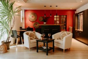 salon z czerwonymi ścianami, białymi krzesłami i stołem w obiekcie Hôtel Le Petit Castel w mieście Antibes