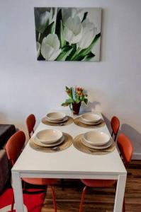 uma mesa branca com cadeiras e pratos e um vaso de flores em Apartament Gardena Olsztyn Jaroty em Olsztyn