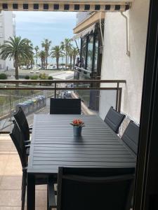 a wooden table and chairs on a balcony with palm trees at Salou Llevant parking gratuit in Salou
