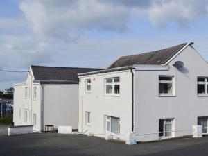 een wit huis met een zwart dak bij Quay Side in Cemaes Bay