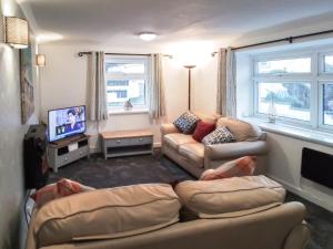 een woonkamer met banken en een flatscreen-tv bij Quay Side in Cemaes Bay