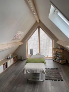 een slaapkamer op zolder met 2 bedden en een groot raam bij Lin et l'autre appartement in Limmen