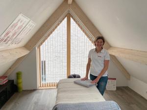 a woman standing next to a bed in a attic at Lin et l'autre appartement in Limmen
