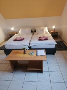 2 Betten in einem Zimmer mit Couchtisch in der Unterkunft Centrum Étterem és Panzió in Őriszentpéter