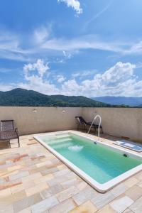 a large swimming pool on a patio with a table and chairs at 2 Quartos com ar, piscina, sacada Gourmet a 1 km da praia Grande in Ubatuba