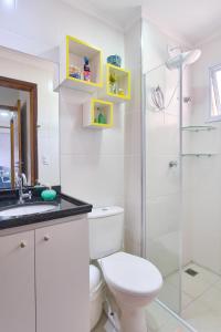 a bathroom with a toilet and a glass shower at 2 Quartos com ar, piscina, sacada Gourmet a 1 km da praia Grande in Ubatuba