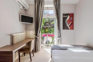 a bedroom with a desk and a bed and a window at Hotel Federale in Lugano