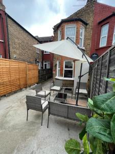 eine Terrasse mit Bänken und einem großen weißen Sonnenschirm in der Unterkunft WoodGreen house in London