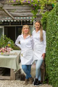two women dressed in white standing next to a table at De Roos Leeuwarden in Leeuwarden