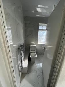a white bathroom with a toilet in a hallway at Good priced Double Rooms in Sherperds bush in London