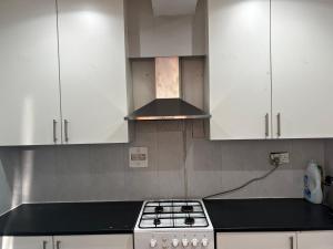 uma cozinha com armários brancos e um forno com placa de fogão em Good priced Double Rooms in Sherperds bush em Londres