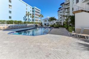 a swimming pool with two chairs and a building at Beach Palms- Unit 102 in Clearwater Beach