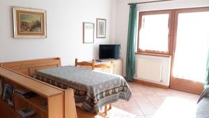 Cette petite chambre comprend un lit et une télévision. dans l'établissement Balcone sulle Dolomiti, à Comelico Superiore