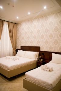 2 Betten in einem Hotelzimmer mit weißer Bettwäsche in der Unterkunft Esposizione Boutique in Rom