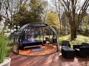 a bed in a gazebo on a wooden deck at Dôme Atmo'sphère, la tête dans les étoiles avec accès piscine in Saint-Évarzec