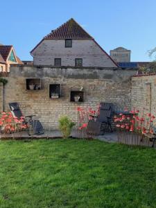 - un bâtiment en briques avec des chaises et des fleurs rouges dans une cour dans l'établissement Vakantiehuisje aan de Ijzer, à Dixmude