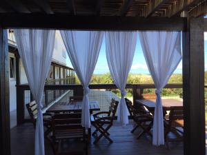 a porch with a table and chairs and a window at Bellapraia Apart Hotel in Rio Grande