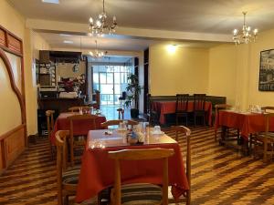 a restaurant with tables and chairs with red table cloth at Hotel Cotopaxi in Latacunga