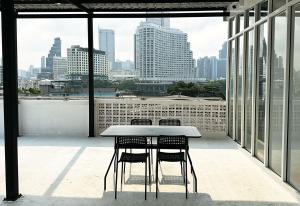 River Home Bangkok في بانكوك: طاولة وكراسي على شرفة مع أفق المدينة