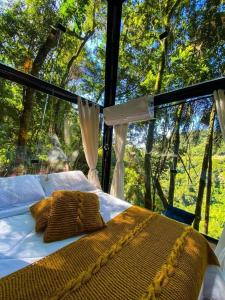 Bett in einem Zimmer mit einem großen Fenster in der Unterkunft Cabanas do Valle in Itaara