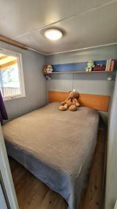 a bedroom with a bed with two stuffed animals on it at Mobil home 6 personnes camping 4* Les Pins Maritimes in Hyères