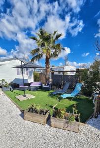 a yard with two chairs and a palm tree at Mobil home 6 personnes camping 4* Les Pins Maritimes in Hyères