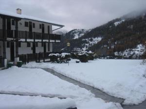 a snow covered street next to a building with a mountain at Salone House in Sauze dʼOulx