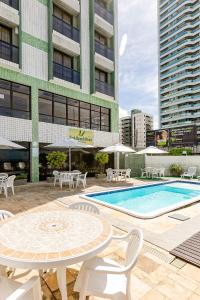 un patio con mesa, sillas y piscina en Yak Beach Hotel Ponta Negra, en Natal