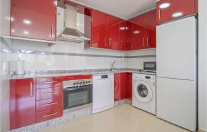 a kitchen with red cabinets and a washer and dryer at Gorgeous Apartment In Conil De La Frontera With Kitchen in Conil de la Frontera