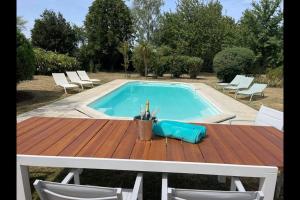 una mesa y una piscina con mesa y sillas en Spacious & Characterful 6 Bed Farmhouse with Pool en Vanzay