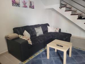 ein schwarzes Sofa im Wohnzimmer mit einem Tisch in der Unterkunft Casa Yoa in Arrecife