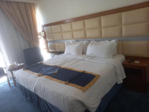 Emaar Elite Al Madina Hotel في المدينة المنورة: غرفة فندق بسرير كبير عليها شراشف ووسائد بيضاء