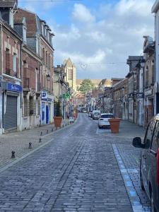una calle adoquinada en una ciudad con coches aparcados en Au coeur de Noyon, en Noyon