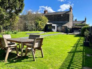 a wooden table and chairs in the yard of a house at Coupling Cottage in Belper