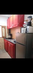 a kitchen with red cabinets and a stainless steel refrigerator at Angelus Meublés 