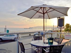 a table and chairs with an umbrella and the ocean at Dory in Sandown