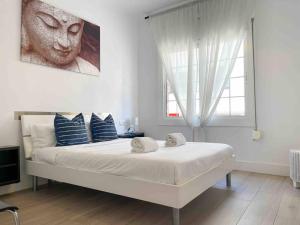 a white bedroom with a large bed with blue pillows at @Hostourist Bcn Fira GranVia Plaza Europa-Justicia in Hospitalet de Llobregat