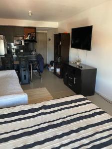 Un dormitorio con una cama y un escritorio con televisión. en Smart Studio Nano en SantaCruz de la Sierra - Barrio Equipetrol, en Santa Cruz de la Sierra