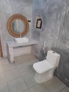 a bathroom with a white toilet and a sink at Villa Pumziko in Kizimkazi