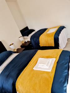 two beds with yellow and blue sheets and a white plate on top at Family Home in Liverpool